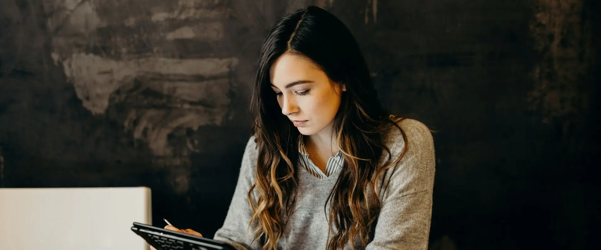 Young female business owners going through her employee payroll on her tablet.